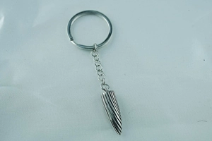 Detailed view of silver bullet-shaped keychain with engraved vertical stripes and ring