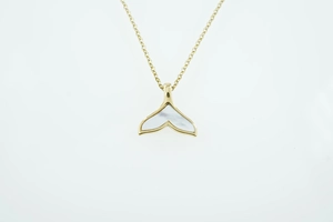 Gedetailleerde close-up van gouden walvisstaart hanger met witte parelmoer inleg