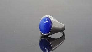 Macro view of a large oval blue cat-eye stone set in a polished stainless steel ring