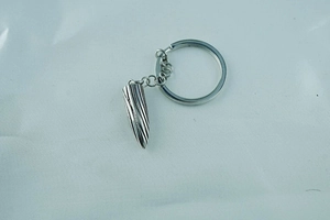 Detail of silver bullet-shaped keychain with intricate spiral texture and sturdy metal ring
