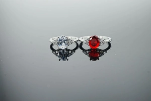 Macro detail of silver rings with oval-cut white and red zircon stones and small diamonds