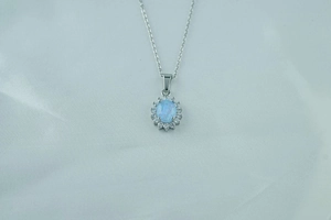 Detailed macro view of the oval opal pendant surrounded by a halo of small white zircons