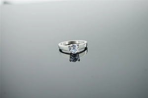 Macro d'une bague moissanite en argent avec serti à griffes sur fond réfléchissant
