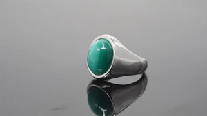 Polished silver ring with oval green stone inlay and deep reflection on black surface