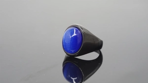 Detail of vintage mens black ring featuring a blue cat-eye stone with clear reflection