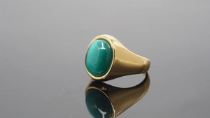 Macro detail of a wide gold ring featuring an oval green gemstone with silk luster