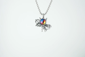Dettaglio di una collana con ciondolo a diavolo argento con ali e occhio colorato
