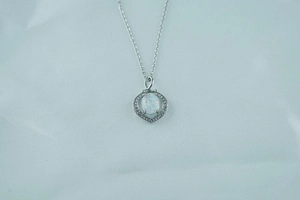 Macro view of opal pendant necklace with heart-shaped zircon halo on silver chain