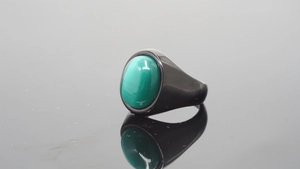 Close-up of vintage black stainless steel ring with a large oval green gemstone inlay