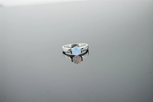 Macro detail of silver ring featuring a round blue-purple opal with side filigree