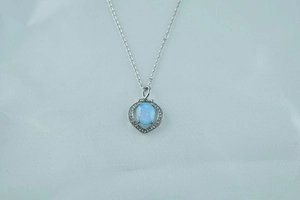 Macro shot of oval opal pendant with zircon halo on silver chain for women