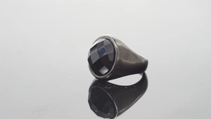 Macro shot of black faceted gemstone set in dark grey matte stainless steel ring