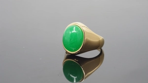 Detailed view of large oval green gemstone set in a polished gold stainless steel ring band