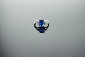 Macro view of silver ring featuring an oval blue gemstone and side accent diamonds