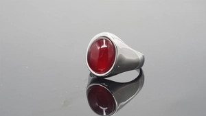 Detail view of a vintage silver ring with an oval red gemstone on a dark reflective surface