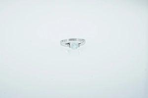 Close-up of minimalist silver ring with polished band and a round white opal stone center