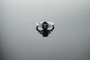 Macro view of vintage silver ring featuring an oval black gemstone with side zircons