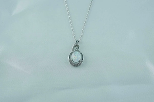 Macro detail of tear-drop opal pendant necklace with sparkling zircon stone accents