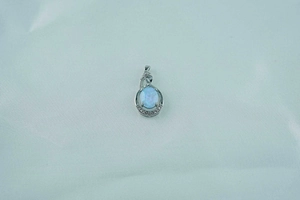 Close-up of silver opal pendant necklace with blue stone and cubic zirconia inlay