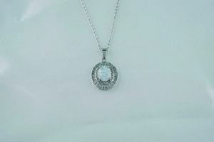 Detail of silver titanium necklace with oval opal pendant and Greek key pattern frame