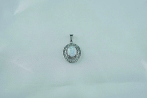 Macro detail of oval white opal pendant with sparkling fire and Greek meander pattern frame