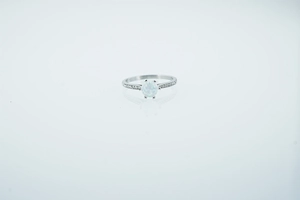 Close-up of a minimalist ring with a round white opal and sparkling side stones