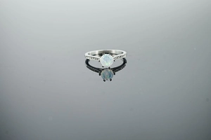 Macro shot of opal ring featuring a polished metal band with side diamond accents