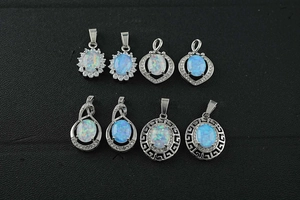 Macro view of eight opal pendants in various silver-plated settings on black display