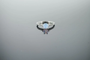Macro shot of silver ring with opal centerpiece and micro-pave side diamonds