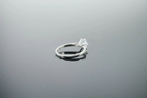 Close-up of minimalist silver opal ring with classic four-prong setting on reflective surface
