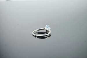 Detail view of round light blue opal ring with four-prong setting and silver steel band