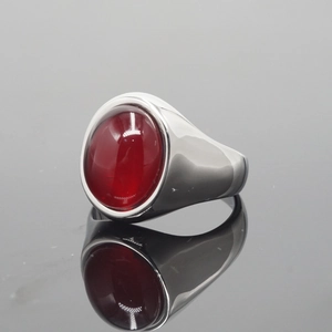Polished stainless steel signet ring with a large oval-cut ruby gemstone on black surface