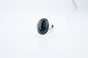 Vista macro di un anello in titanio a fascia larga con un grande cabochon ovale nero