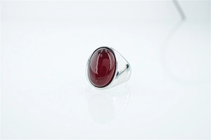 Macro di una grande pietra preziosa rossa ovale incastonata in un anello da uomo in acciaio