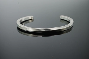 Macro detail of brushed stainless steel Mobius cuff bracelet on black mirror background