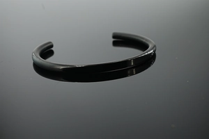 Detailed macro view of the black polished stainless steel C-shaped groove cuff bracelet