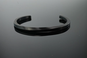 Close-up of minimalist matte black Mobius twist cuff bracelet with reflective mirror effect