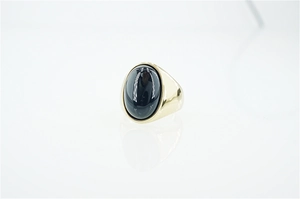 Dettaglio macro di un anello da uomo in acciaio al titanio con agata nera ovale e oro