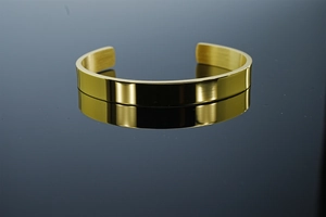 Macro detail of high-polish mirror finish and brushed inner band on golden titanium cuff