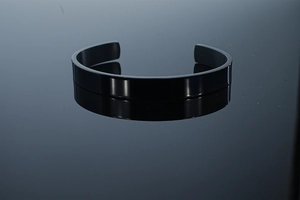 Detail of black stainless steel open bangle showing brushed metal texture and polished edges