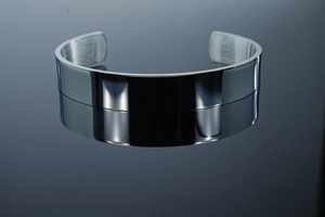 Macro view of mirror-polished silver cuff bracelet showing brushed interior and reflection