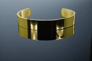Detail of gold mirror-polished C-shaped adjustable cuff bracelet with smooth finish