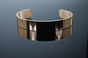 Macro detail of mirror polished surface and brushed metal texture on adjustable cuff bracelet