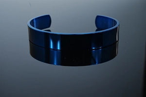 Macro shot of polished deep blue titanium steel cuff bangle with mirrored reflection