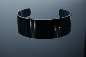 Macro view of polished black stainless steel cuff bracelet with high mirror finish