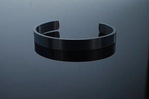 Dettaglio ravvicinato di un bracciale rigido a C in acciaio inossidabile nero opaco spazzolato