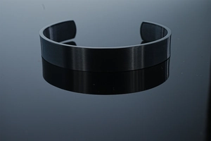 Dettaglio macro del bracciale rigido regolabile in acciaio inossidabile nero opaco spazzolato