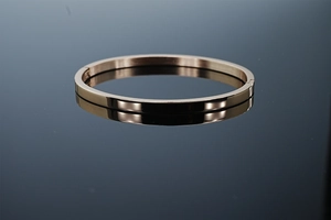 Détail d'un bracelet jonc en acier inoxydable poli couleur or rose au fini miroir