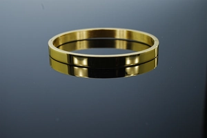 Vue de dessus d'un bracelet jonc minimaliste en acier poli doré sur une surface réfléchie
