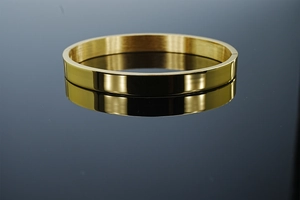 Détail macro d'un bracelet jonc en acier inoxydable doré avec une finition métal brossé